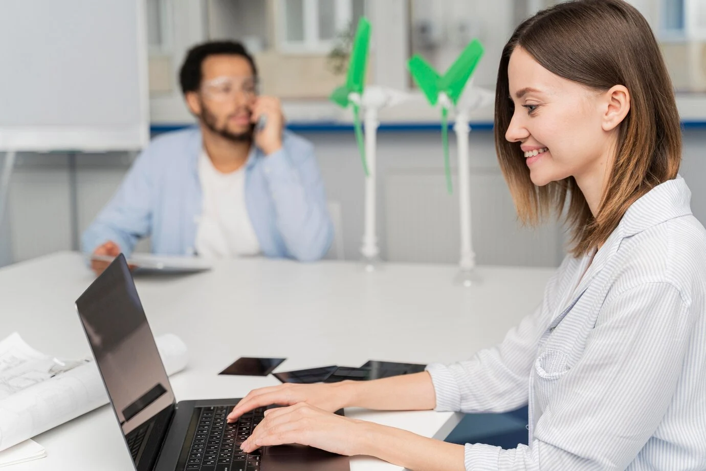 girl using laptop and behing man in phone call